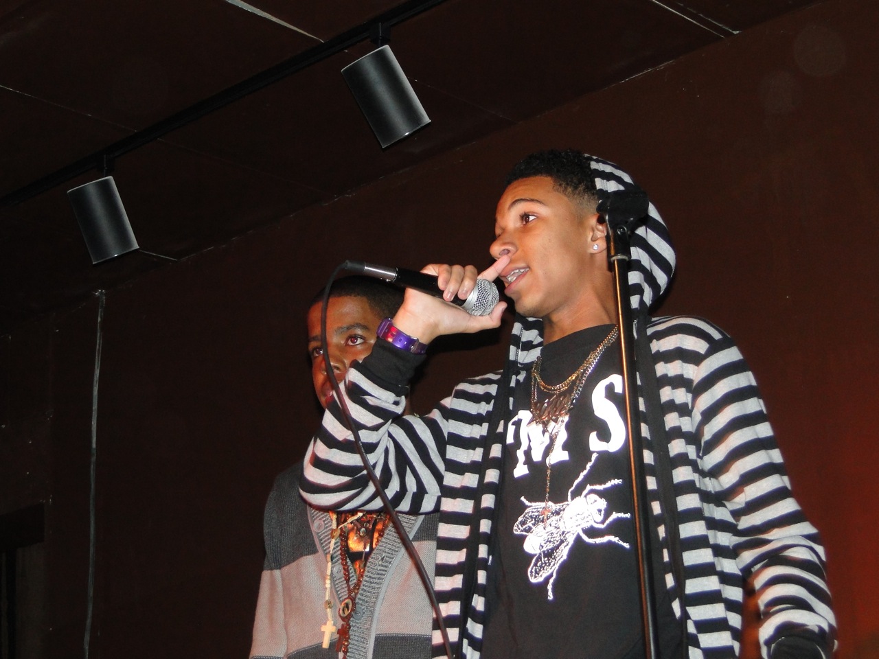 A young vocalist performing into a microphone during a T.W.I.G.S. event.